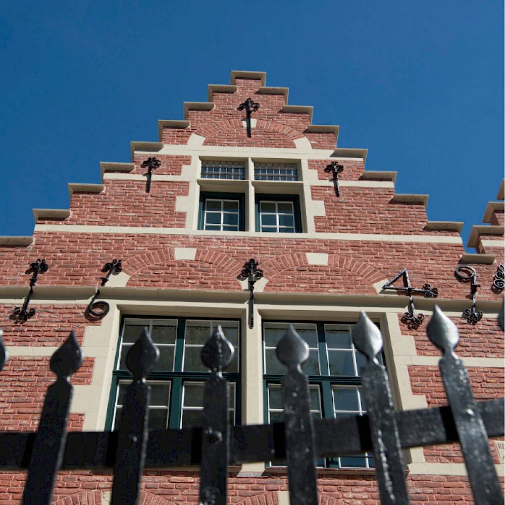 voorgevel van een gerenoveerd herenhuis met een zwart hekken op de voorgrond