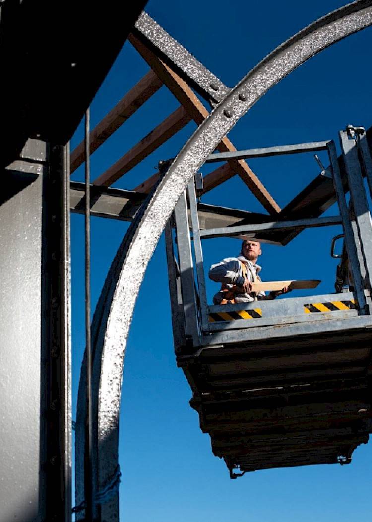 Man aan het werk aan een houten dakconstructie met behulp van een speciale lift